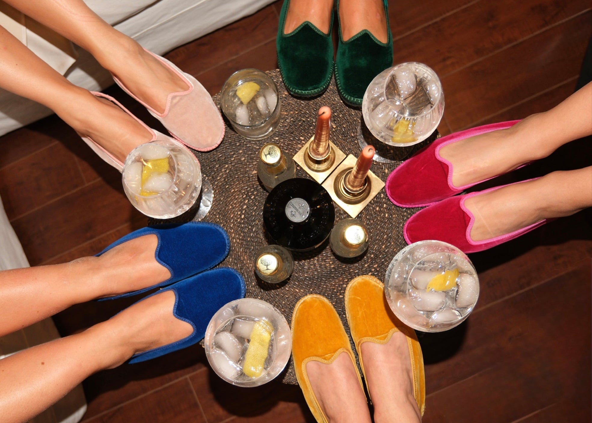 People wearing colorful shoes around a table with drinks and a candle.